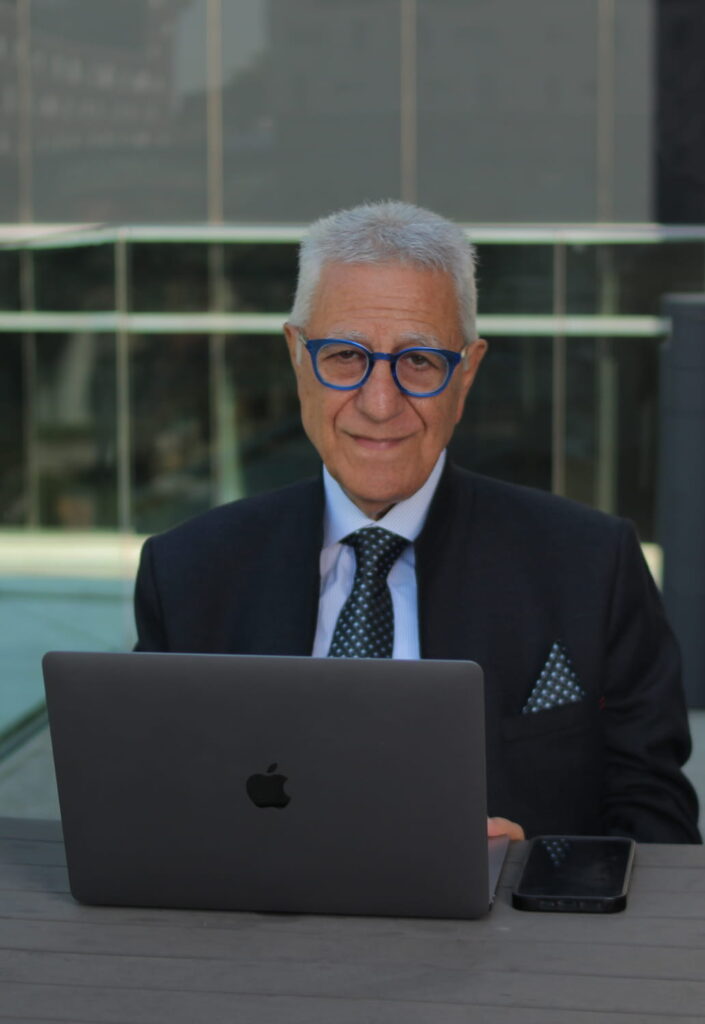 Portrait of Chucrallah Tabib looking at you while sitting in front of his laptop computer