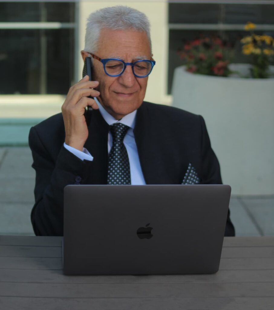 Portrait of Chucrallah Tabib looking at his laptop computer while responding to a phone call